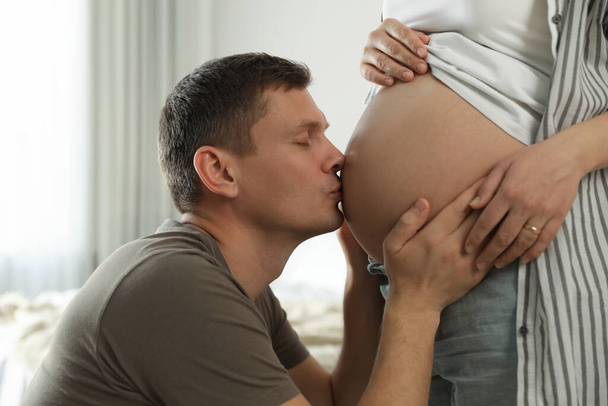 Young pregnant woman with her husband at home, closeup - Фото, изображение