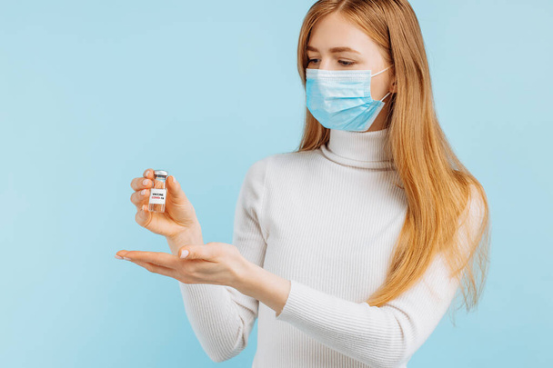 Doctor holding a vial with a dose of covid 19 corona virus vaccine for injection, on a blue background, Coronavirus treatment, vaccination concept - 写真・画像
