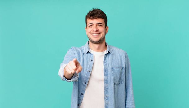 handsome man pointing at camera with a satisfied, confident, friendly smile, choosing you - Foto, Bild