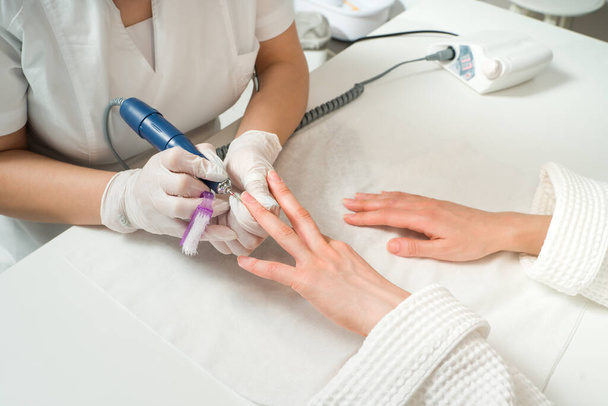 Žena v nehtovém studiu dostává manikúru od kosmetičky s pilníkem na nehty. Krása a péče o ruce zblízka. - Fotografie, Obrázek