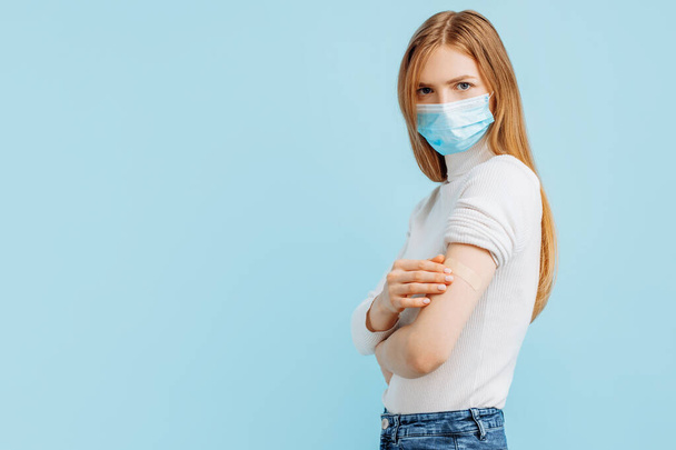 Healthy young woman in medical mask vaccinated, immunity, blue background, recommended vaccination concept, vaccination, vaccinated patient, vaccine deployment program - Φωτογραφία, εικόνα
