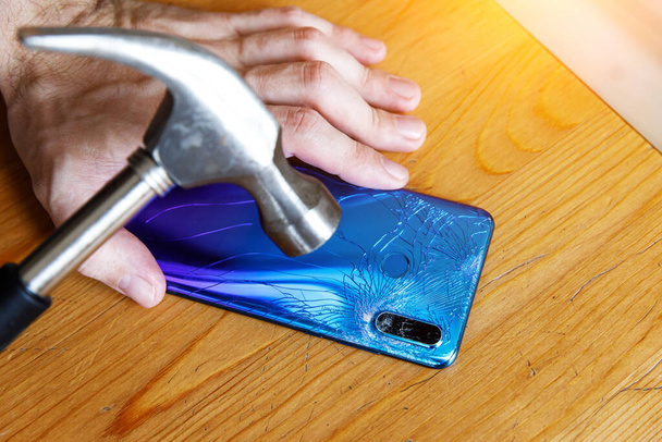 Broken smartphone camera and hammer on wooden background - Фото, зображення
