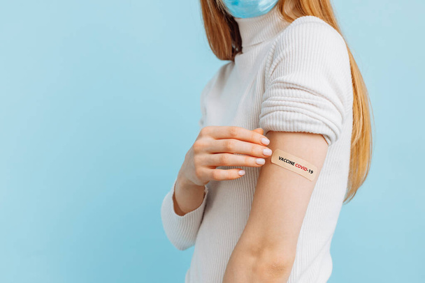 Healthy young woman in medical mask vaccinated, immunity, blue background, recommended vaccination concept, vaccination, vaccinated patient, vaccine deployment program - 写真・画像