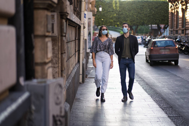 Una pareja recién casada camina por las calles del centro, usan máscaras protectoras contra la propagación de la pandemia del coronavirus. - Foto, imagen