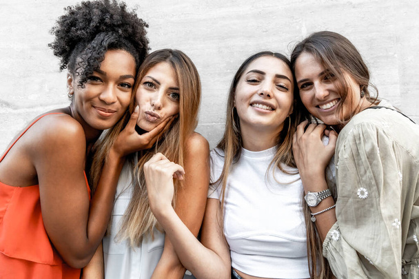 Portret międzyrasowych dziewczyn z genów uśmiechających się i żartujących oglądając aparat fotograficzny, koncepcję lub przyjaźń lub młodych ludzi z różnych krajów nawiązujących więź i bawiących się razem. - Zdjęcie, obraz