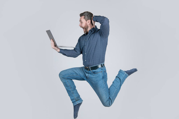 surprised energetic jumping man businessman running while working online on laptop hurry up for shopping, surprise. - Photo, image