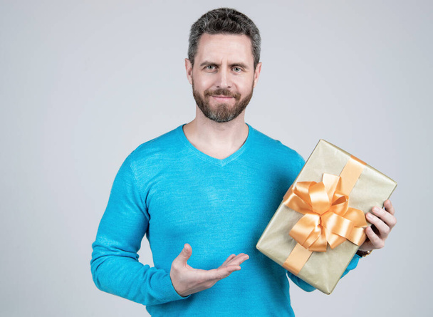 όμορφος ώριμος άνδρας επιχειρηματίας με γενειάδα κρατώντας δώρο ή κουτί δώρου, γενέθλια. - Φωτογραφία, εικόνα