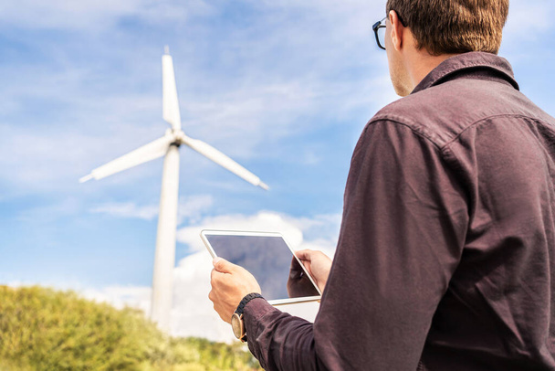 Engineer and tablet in wind power field working for renewable sustainable energy. Technician in industrial electricity generation and green environmental project. Turbine engineering and maintenance. - Photo, Image
