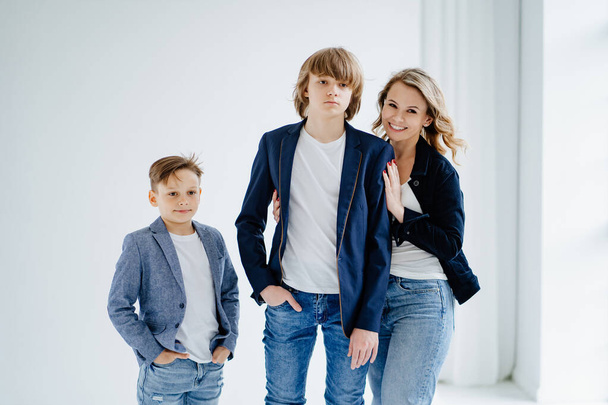 A mother with two sons in blue clothes have fun and poses for a photo shoot - Фото, изображение