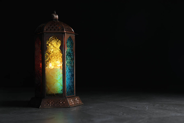 Decorative Arabic lantern on grey table against black background, space for text - Photo, Image