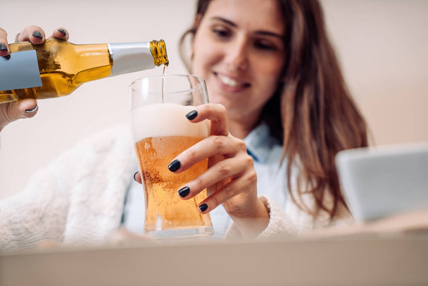 young woman pours a bottled beer into the glass - Foto, imagen