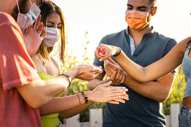 Groupe de jeunes gens désinfectant ensemble leurs mains avec un bot - Photo, image