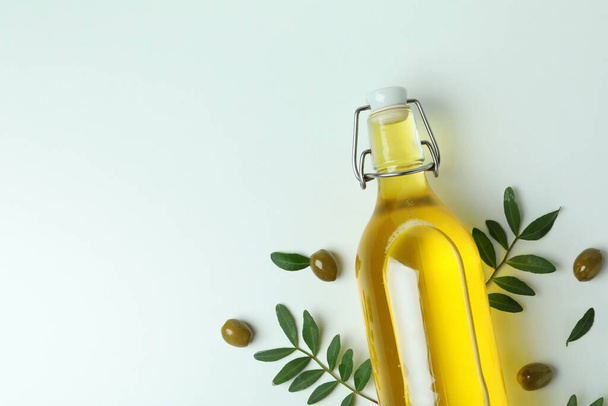 Бутылка масла, оливок и веток на белом фоне - Фото, изображение
