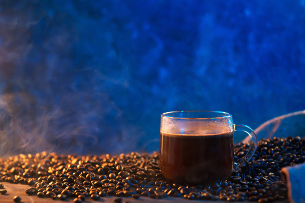 グラスコーヒーカップ、ローストコーヒー豆、トレンディーな青のバックライト - 写真・画像