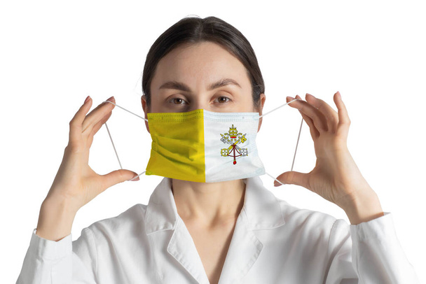 Respirator with flag of Vatican Doctor puts on medical face mask isolated on white background. - Photo, Image