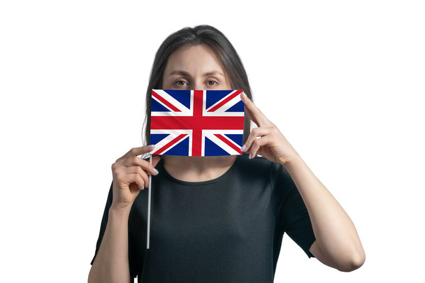 Glückliche junge weiße Frau mit der Flagge Großbritanniens und bedeckt ihr Gesicht isoliert auf weißem Hintergrund. - Foto, Bild