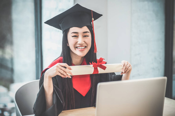 Cute asian smiling graduate holding her diploma and looking happy - Foto, imagen