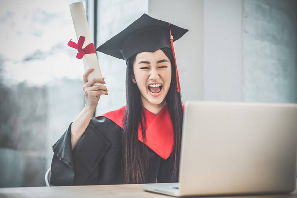 Cute asian smiling graduate holding her diploma and looking happy - Foto, imagen