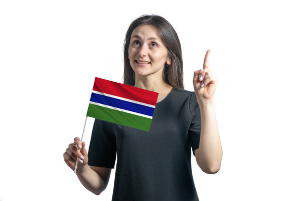 Happy young white woman holding flag of Gambia and points thumbs up isolated on a white background. - Photo, Image