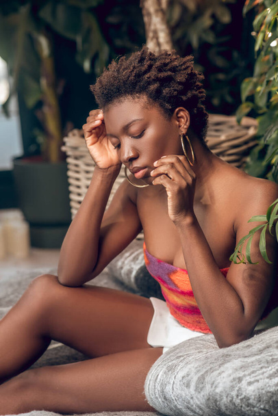Dark-skinned young woman in a bright top and white shorts looking thoughtful - Foto, immagini
