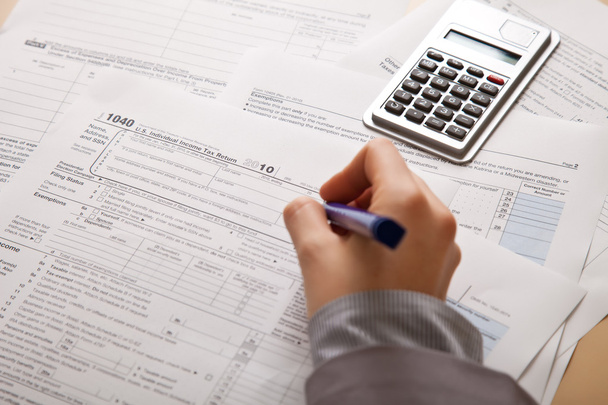 Woman hand filling income tax forms with calculator - Photo, Image