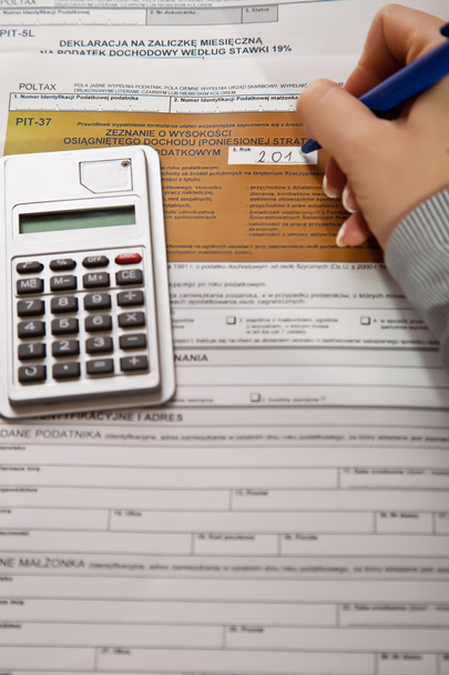 Woman hand filling income tax forms with calculator - Foto, Bild