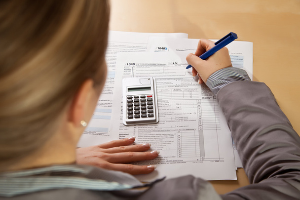Woman hand filling income tax forms with calculator - Photo, Image