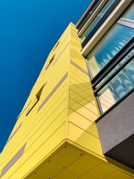 Vista de ángulo bajo de la fachada amarilla de un moderno edificio de apartamentos nuevo y elegante. - Foto, imagen
