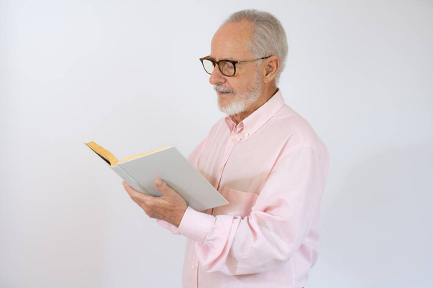 Студийный снимок пожилого человека, читающего книгу на белом фоне - Фото, изображение