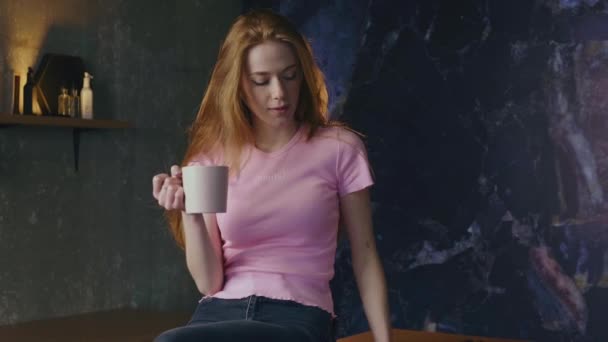 Femme caucasienne avec des cheveux au gingembre et des taches de rousseur boit un café tout en utilisant une tablette  - Séquence, vidéo