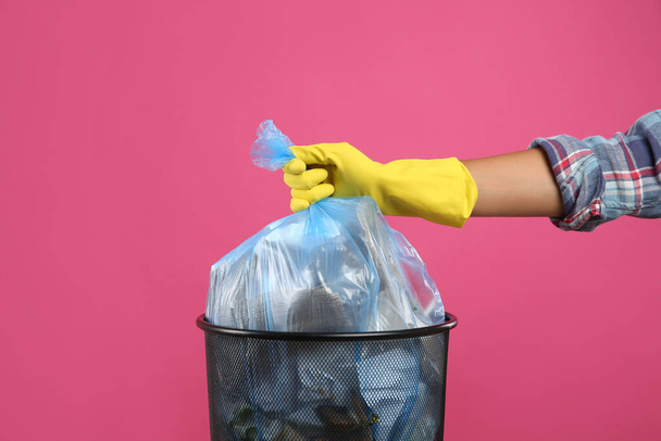 Woman taking garbage bag out of bin on pink background, closeup - Photo, image