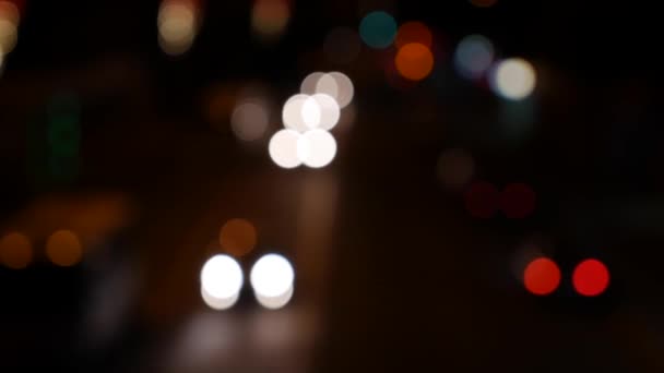 Wunderschönes glitzerndes Bokeh vor dunklem, verschwommenem Hintergrund in der Nacht. Die runden bunten Bokeh leuchten von Autolichtern auf der Stadtstraße. Unscharf und verschwommen. Unfokussierte Stadtbeleuchtung. Der Verkehr brummt. Abstrakt - Filmmaterial, Video