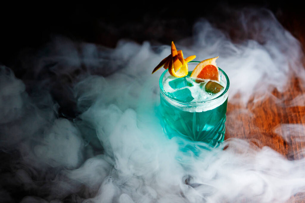 Refreshing cocktail with ice and orange slice. Summer green drink. Bar concept. Smoke. - Photo, Image