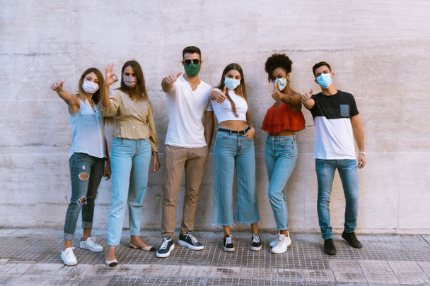 Nuevo concepto de estilo de vida normal de los jóvenes del milenio con máscaras faciales de moda bajadas juntas durante la segunda crisis de cuarentena - Foto, Imagen