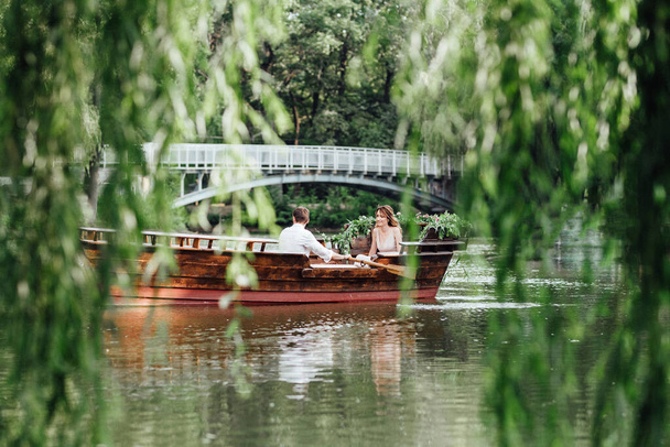 un viaje en barco para un chico y una chica a lo largo de los canales y bahías del río cubierto de sauces salvajes - Foto, Imagen