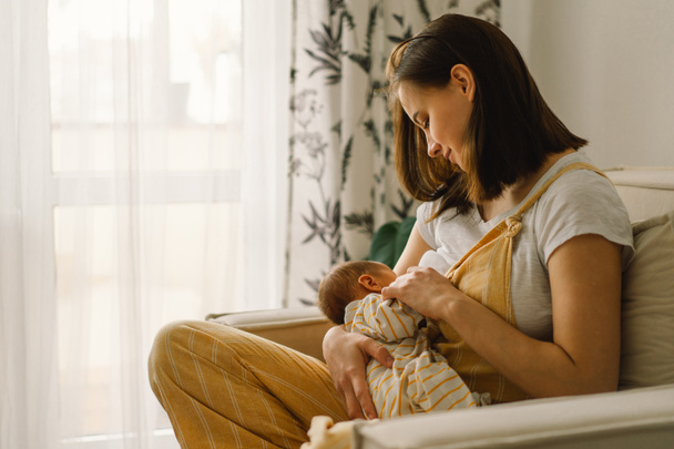 Newborn baby boy sucking milk from mothers breast. Portrait of mom and breastfeeding baby. - Фото, изображение