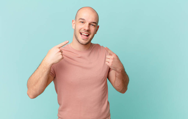 bald man smiling confidently pointing to own broad smile, positive, relaxed, satisfied attitude - Fotó, kép