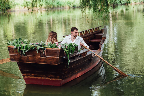 eine Bootsfahrt für einen Jungen und ein Mädchen entlang der Kanäle und Buchten des Flusses, die mit wilden Weiden bewachsen sind - Foto, Bild