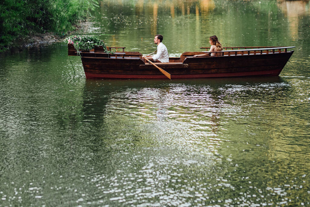 a boat trip for a guy and a girl along the canals and bays of the river overgrown with wild willows - Fotoğraf, Görsel