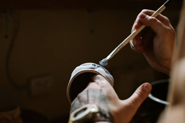 Tattooed man hands painting on clay cup - Φωτογραφία, εικόνα
