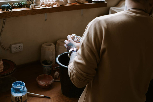 Татуйований чоловік рук малює на глиняній чашці
 - Фото, зображення