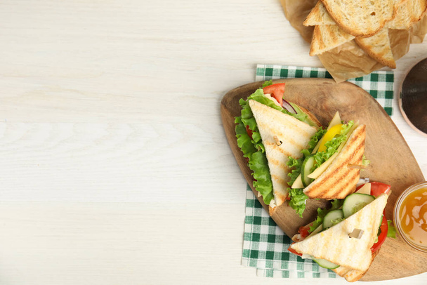 Heerlijke sandwiches met groenten en kaas op witte tafel, plat gelegd. Ruimte voor tekst - Foto, afbeelding