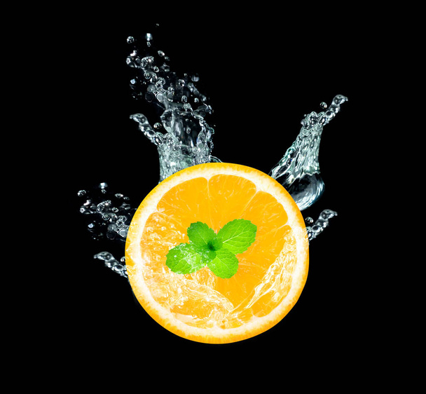 Fruta naranja fresca en rodajas en salpicadura de agua aislada sobre fondo negro - Foto, Imagen