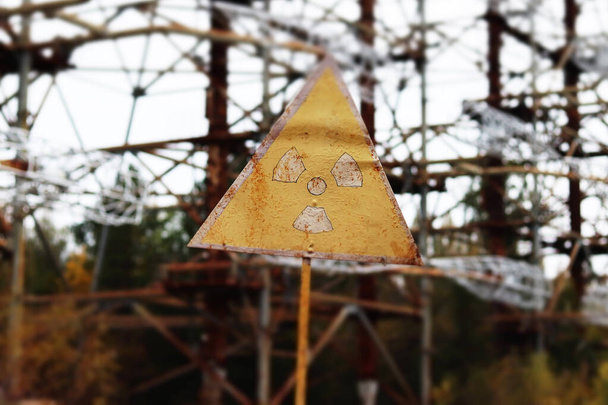 Antiguo signo de radiación amarilla contra el complejo de antenas Duga Radar. Zona de exclusión de Chernobyl, Ucrania. Efecto de desplazamiento de inclinación - Foto, Imagen