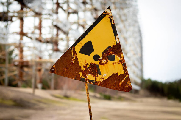 Stará žlutá radiační značka proti anténnímu komplexu Duga Radar. Černobylská vyloučená zóna, Ukrajina. Efekt posunu náklonu - Fotografie, Obrázek