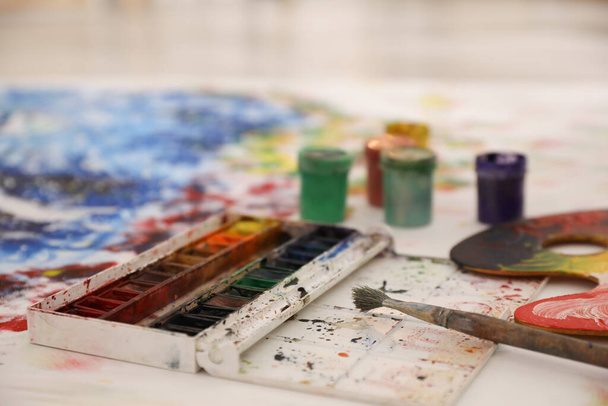 Box of paints and brush on abstract picture - 写真・画像