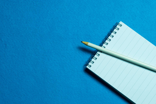 blank page of notebook and pencil on light blue background - Photo, Image