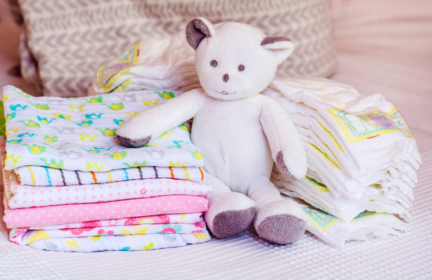 Stack of Eco Friendly Textile Diapers and Cotton Diapers with Teddy Bear - Photo, image