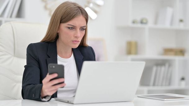 Beautiful Businesswoman using Smartphone and Laptop in Office  - Foto, Imagem