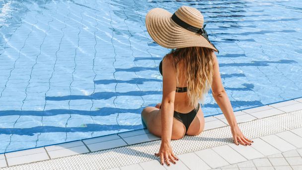 Léto. Šťastná mladá sexy dívka v bikinách plavkách, slunečních brýlích a slamáku relaxační v modré bazénové vodě. Bazén vody, baví a těší cestovní dovolenou - Fotografie, Obrázek